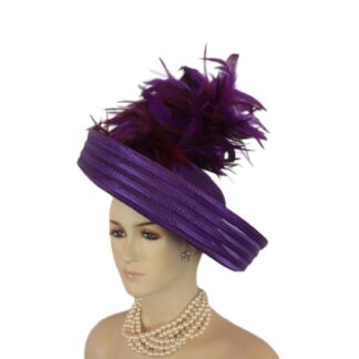 Elevate your fashion statement with our exquisite feathered Avant Garde Royal Purple Haute Couture roll-up sheer wide brimmed hat. This striking designer headpiece is adorned with vibrant, deep multi colored purple rooster hackle feathers that stand in an upright position, enhanced by a mesmerizing iridescent sheen. This luxurious hat transforms any outfit into a high-fashion masterpiece, making it the ideal accessory for the mother of the bride, the bride herself, or wedding guests eager to leave a memorable impression. This special occasion dress hat is an essential addition for luncheons, church services, festive gatherings, and iconic horse racing events such as the Kentucky Derby, Breeder's Cup, The Preakness Stakes, Royal Ascot, Grand National Steeplechase, Prix de l'Arc de Triomphe in France, Pegasus World Cup, Dubai World Cup, Virginia World Cup, and Melbourne Cup. This glamorous headpiece, with its unique design, beautifully complements your wardrobe while embodying the elegance synonymous with luxurious feathered accessories.